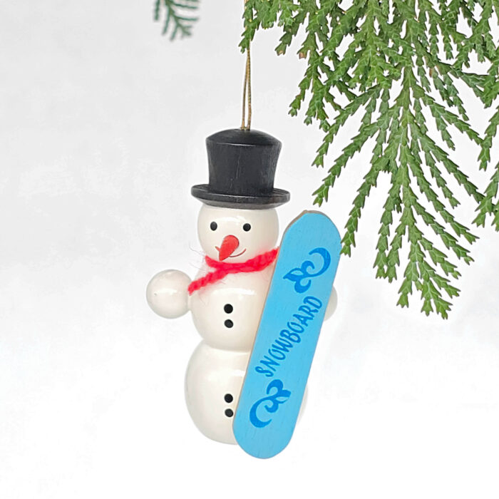 kleiner weißer Holzschneemann hängend mit blauem Snowboard
