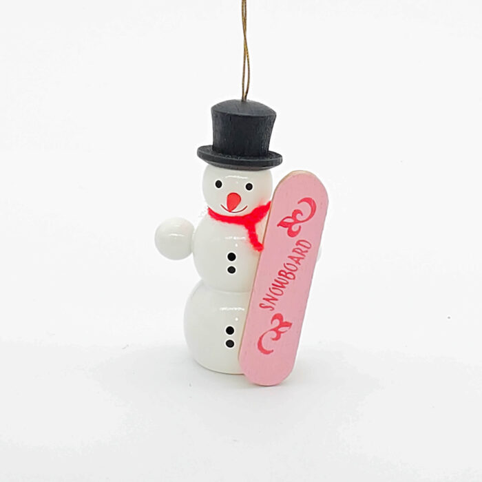 kleiner weißer Holzschneemann hängend mit pinkem Snowboard