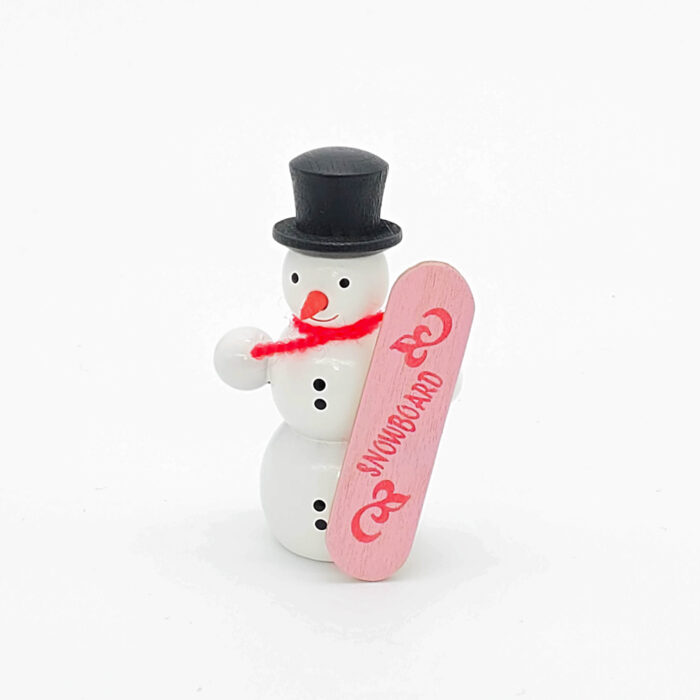 kleiner weißer Holzschneemann mit pinkem Snowboard